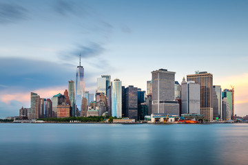 New York, New York, USA downtown city skyline at dusk on the harbor.