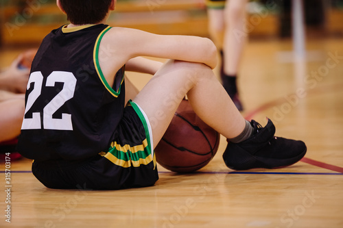 Junior basketball player sitting on the floor in backetball court photo