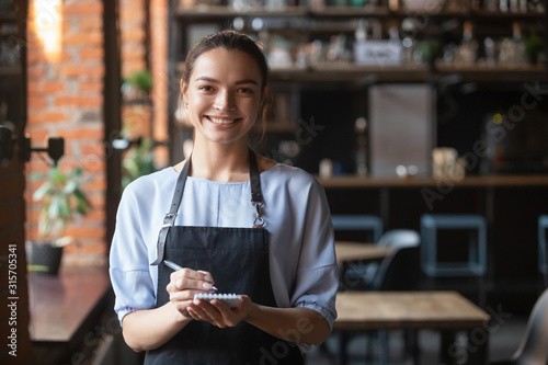 Portrait of smiling waitress in apron looking at camera