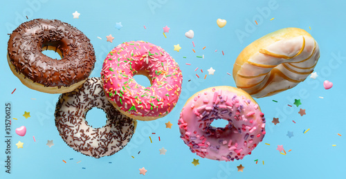 Flying donuts with sprinkle on blue background. photo