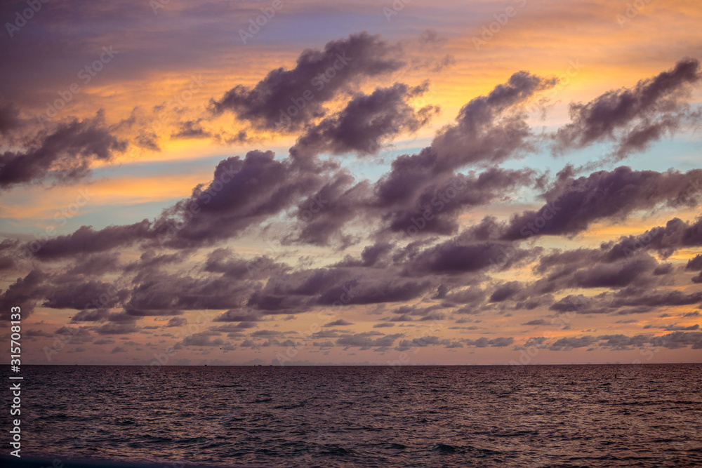 purple golden clouds over ocean at golden hour