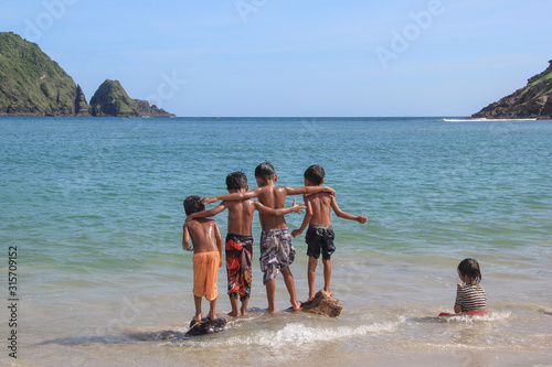 Kids playing, sitting and jumping in water at the seaside. Cute kids having fun on sandy beach in summer. Group of happy kids play on background of empty sunset beach.clean beach with the white sands. © Ihsan