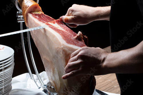 Manos corte de jamón ibérico con cuchillo. Hands cutting Iberian ham with knife.