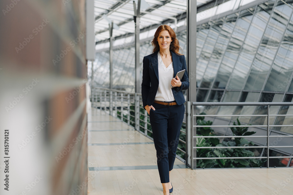 Confident businesswoman holding a tablet in a modern office building Confident businesswoman holding a tablet in a modern office building