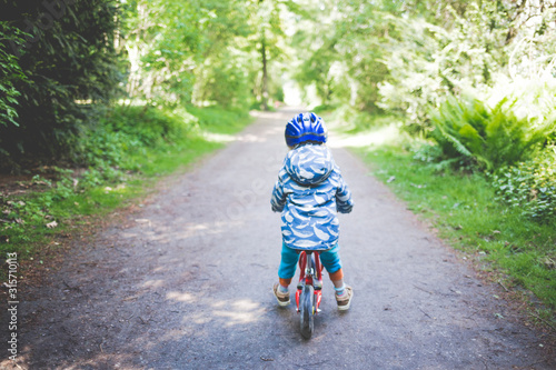 Back view of toddler girl with blue cycling helmet on bogie wheel