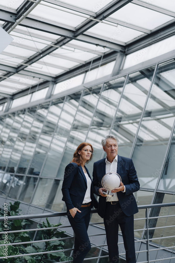 Businessman and businesswoman holding globe in modern office building Businessman and businesswoman holding globe in modern office building