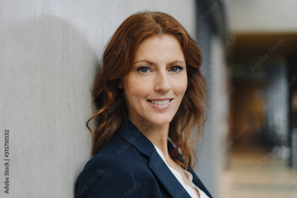 Portrait of a smiling businesswoman at concrete wall