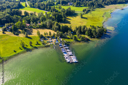 Germany, Bavaria, Seeshaupt, Aerial view of boats moored along jetty on green shore of Lake Starnberg photo