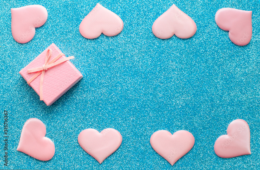 Obraz premium Valentines day pattern background flat lay pink hearts and a pink gift box with rose ribbon on a glittering classic blue background with copy space. love wedding romantic concept, minimal top view
