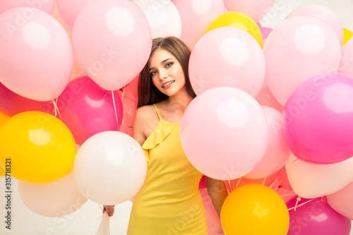 colorful portrait of young beautiful model with a lot of pink yellow and white baloons
