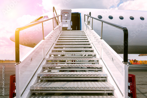 Passenger airplane with a boarding steps in the sun rays