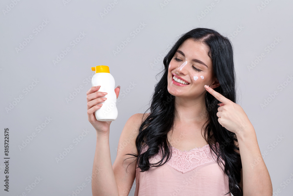 Young woman with sunscreen on a gray background Young woman with sunscreen on a gray background