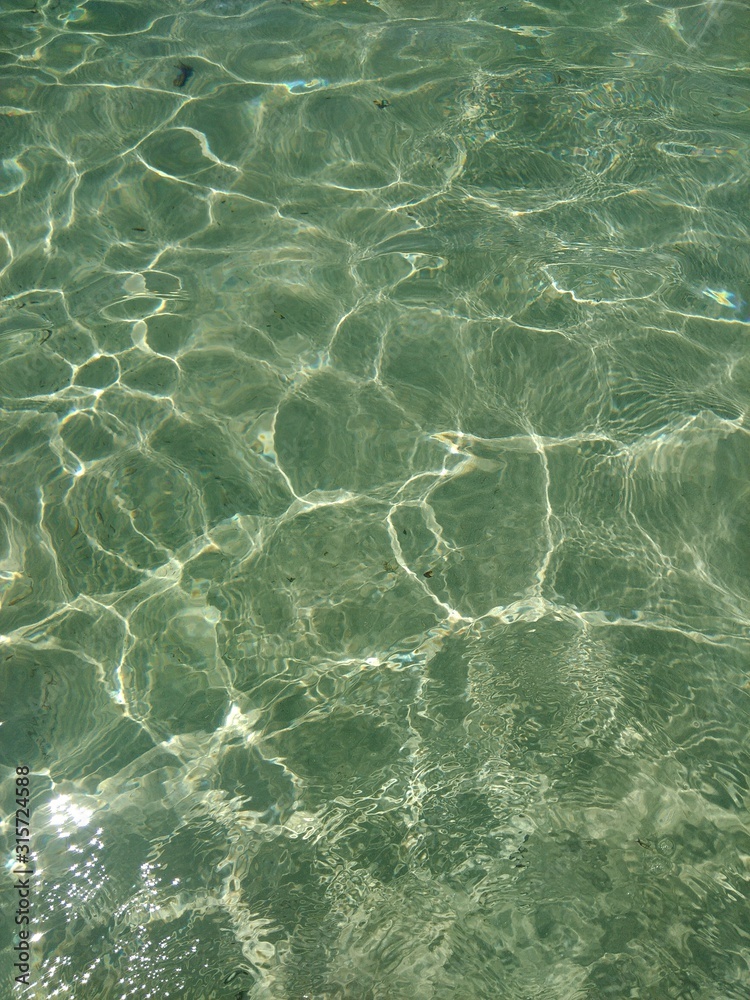 Obraz premium close up of clear sea and sunlight reflecting off sandy sea bed