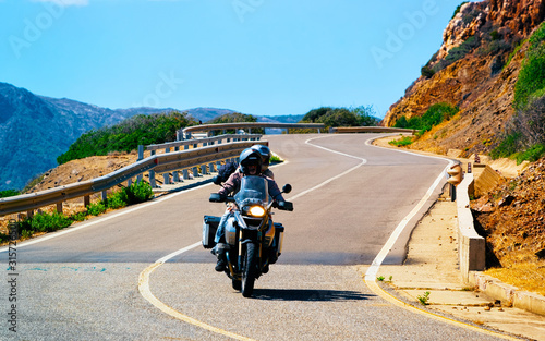 Motorcycle on road at Costa Smeralda in Sardinia Island in Italy in summer. Motorcyclist driving scooter on highway of Europe. Man on moped at motorway. Olbiai province. Mixed media.
