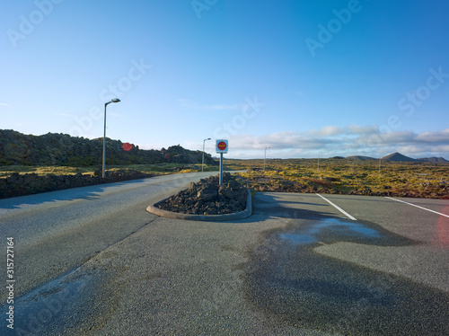 Big parking area with lots of parking spaces in Iceland in a volcanic landscape with rocks and moss. Driveway at one side. Backplate for automobile industry and cgi.