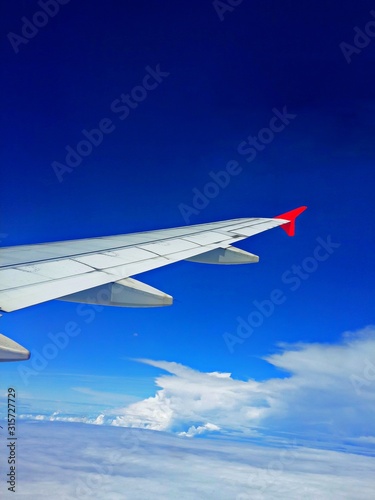 Scenery from window looking at Airplane wing with blue sky and clouds. Top view scenery showing city landscape perfect natural river  green forest on mountain at Laos. Travel Transportation concept.