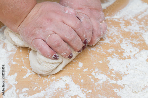 Kneading dough with flour on a wooden table at home
