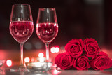 Wine and roses on table surrounded by candles 