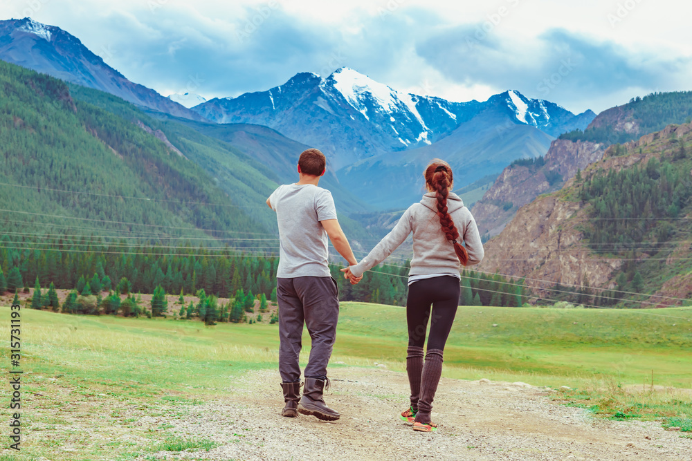 the couple stands against the background of mountains