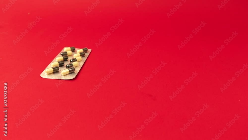 hands take a bunch of packages with pills on a red background. hands take a bunch of packages with pills on a red background.