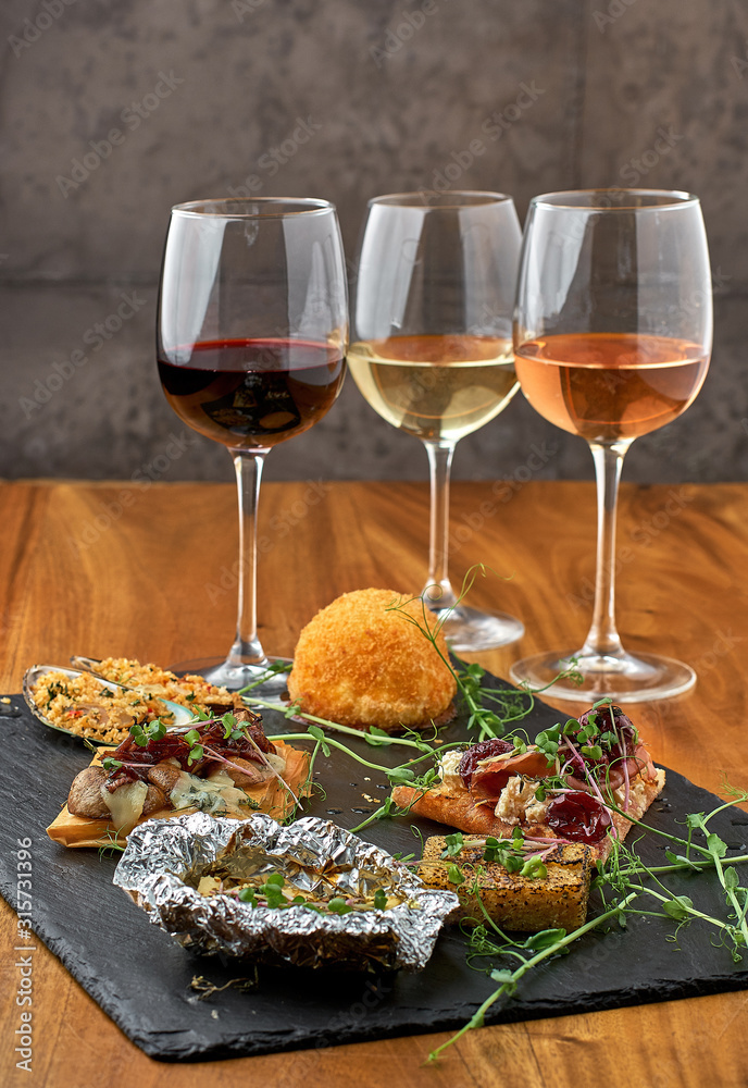 Glasses of red, pink and white wine with various types of cold snacks. Food and drink concept.