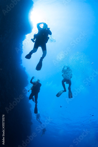 Silhouette of scuba divers and sunlight underwater in the Red Sea. 