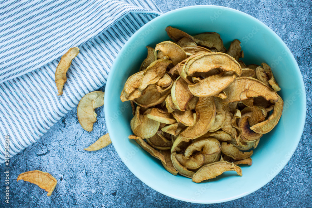 Dried Apple slices in a ceramic mint Cup on a grey textured background top view with space for copying Dried Apple slices in a ceramic mint Cup on a grey textured background top view with space for copying
