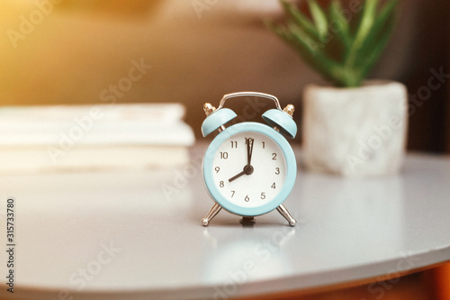 Alarm clock on blurred bedroom background in the morning, interior design details