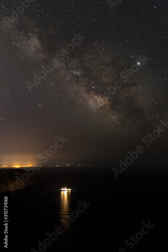 Milky way and stars over a harboured marine research ship near Es Vedra in Ibiza