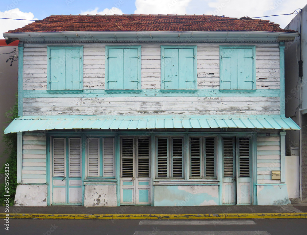 Typical wooden and rusted house in Martinique, French West Indies. Tropical blue and white windows