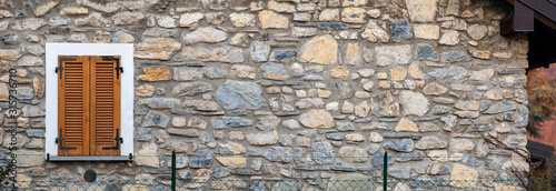 ancient house stone wall, with window shutters in light wood, panorama banner