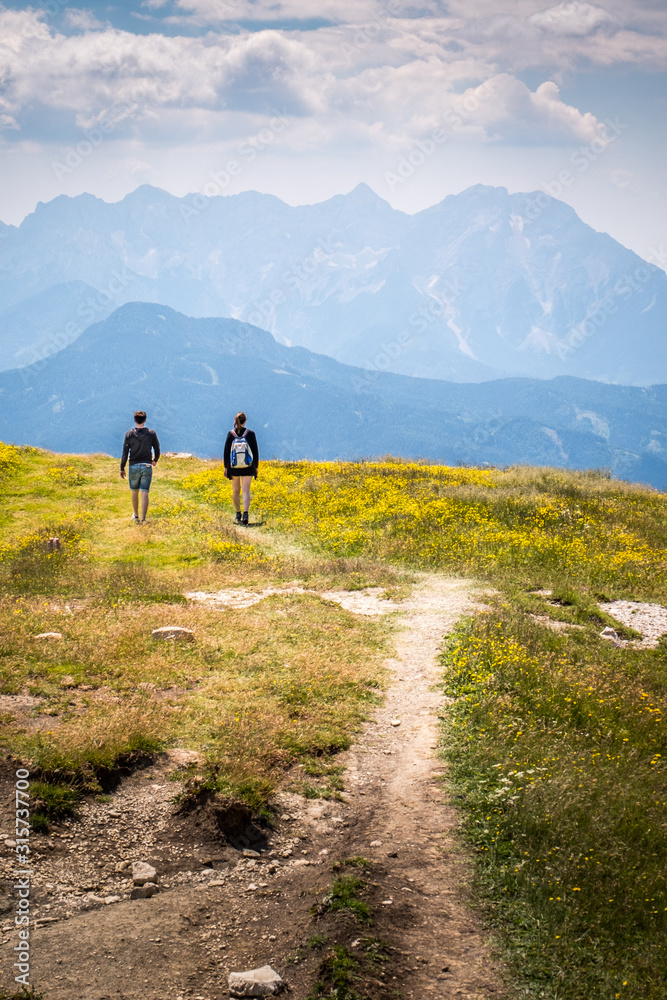 Hiking couple on mountain Hochobir, Austria, with Kamnik–Savinja Alps - obrazy, fototapety, plakaty 