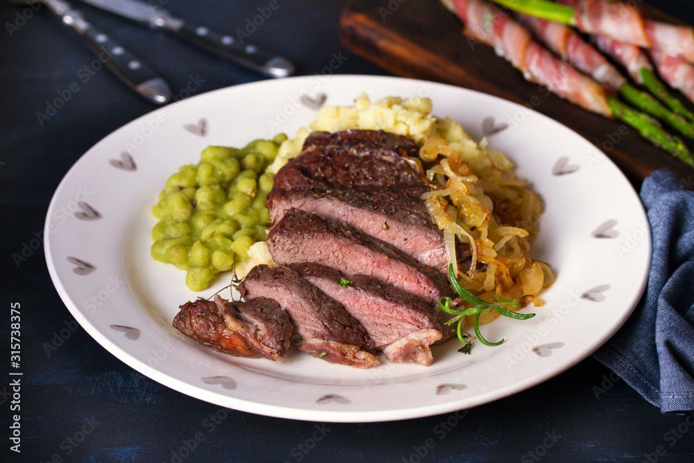 Grilled fillet beef steak with mashed potato, peas and fried onion