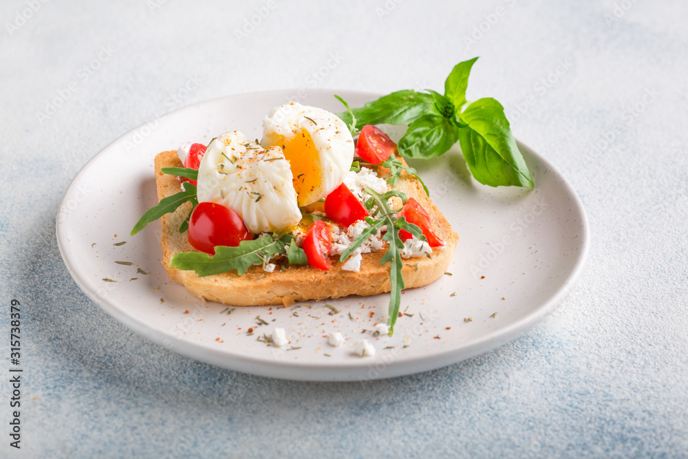 French breakfast concept. Poached egg on toasted bread with cherry tomatoes, cheese and herbs on a boiled background French breakfast concept. Poached egg on toasted bread with cherry tomatoes, cheese and herbs on a boiled background