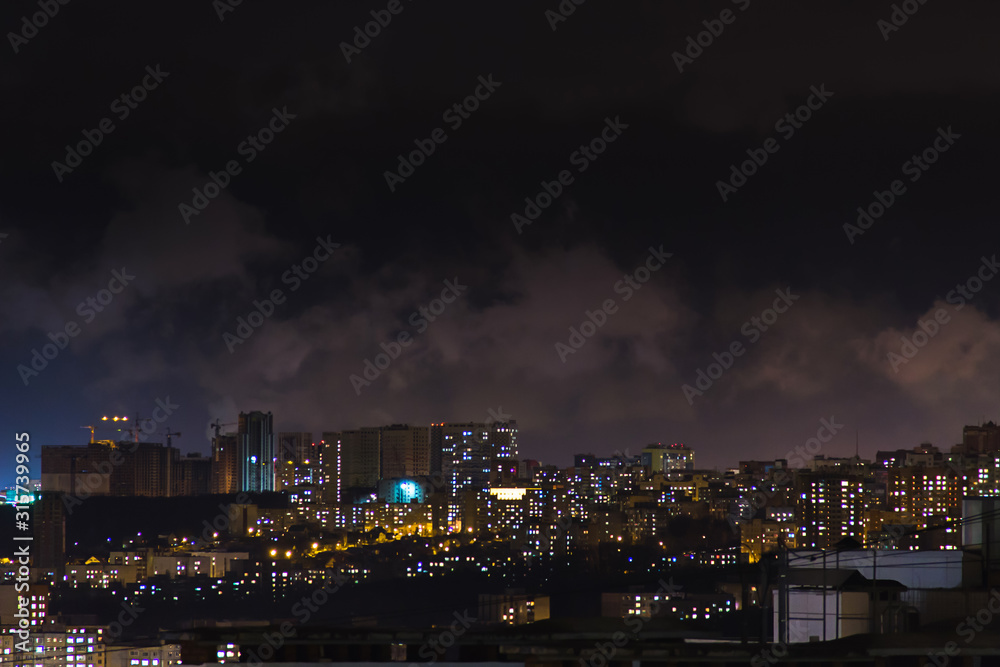 Evening shot of a city on hill buildings.Top aerial panoramic view. Construction cranes on new residential areas