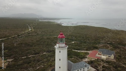 4K summer foggy day aerial drone video of famous Danger Point Lighthouse on southern point of Walker Bay peninsula near Indian Ocean coastal town Gans Bay, Garden Route, Western Cape, South Africa