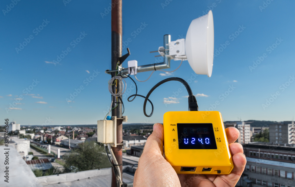 Outdoor wifi radio connection maintenance. Hand detail holding digital  gauging instrument. Testing a power supply voltage of wireless access  point. Network hardware device for microwave internet link. Stock Photo |  Adobe Stock