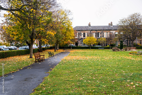 Public park with a paved path lined with wooden benches in a residential distric on a cloudy autumn day. Portobello Beach, Edinburgh, Scotland, UK. photo