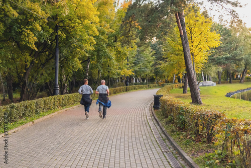 Young man and senior man are jogging in the morning autumn park