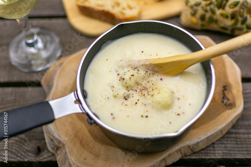 Hearty cauliflower soup in a saucepan with a wooden spoon. Rustic arranged