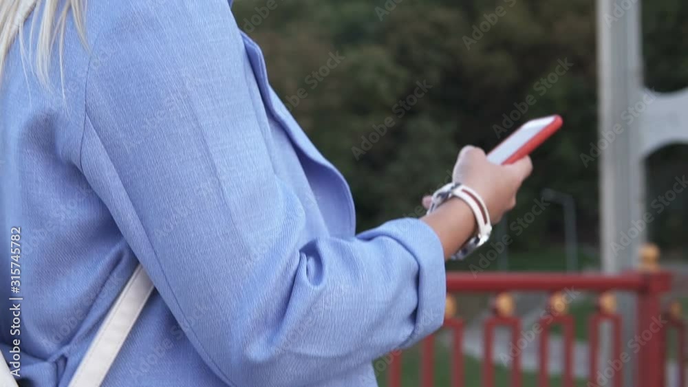 A beautiful woman in stylish clothes walks on a pedestrian bridge in a big city and uses the phone A beautiful woman in stylish clothes walks on a pedestrian bridge in a big city and uses the phone