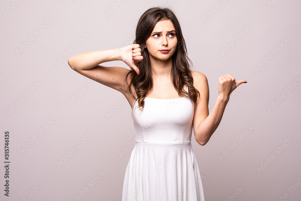 Beautiful young woman with thumbs down pointed side isolated on white background Beautiful young woman with thumbs down pointed side isolated on white background