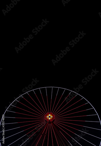 Ferris wheel at night carnival entertainment place hear shape lamp illumination frame black background empty copy space for text, vertical picture