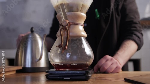Barista pouring hot water into filter with coffee. Alternative methods of brewing coffee. Brewing coffee in a chemex. photo