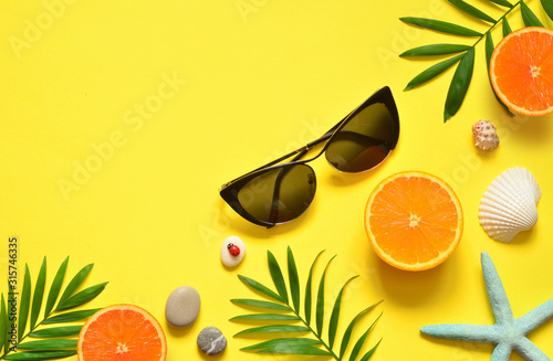 Tropical Summer Beach Background. Palm Trees Branches, tarfish, seashell, sunglasses and orange on yellow summer background. Travel. Summer concept. photo