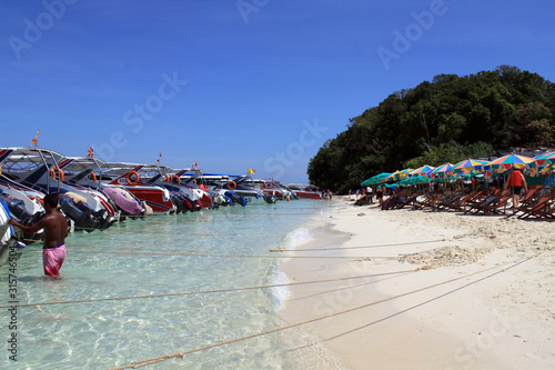 The parking of numerous boats near the summer, clean beach with blue water