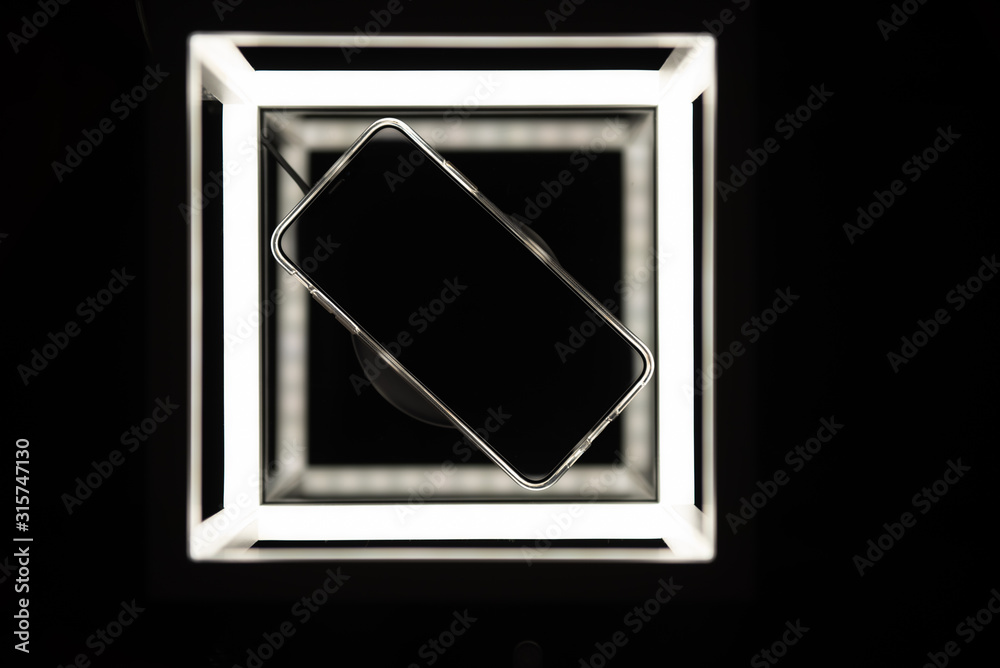 Mobile phone on wireless charger, loading, with black screen, on black background with led lights Mobile phone on wireless charger, loading, with black screen, on black background with led lights