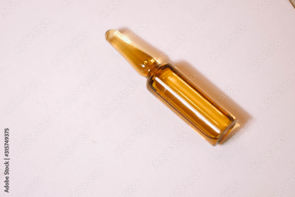 Naklejka premium Brown ampoule with medicine on light background. Illness treatment. Pharmaceutical business. Skincare products