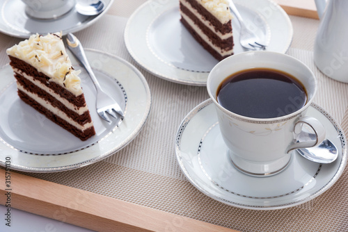 Tasty cocoa cakes with cups of coffee on a wooden tray