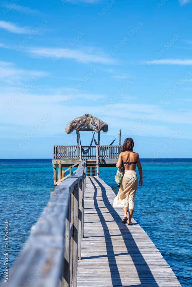 A young woman walking along the beach of Sandy Bay on Roatan Island. Honduras A young woman walking along the beach of Sandy Bay on Roatan Island. Honduras